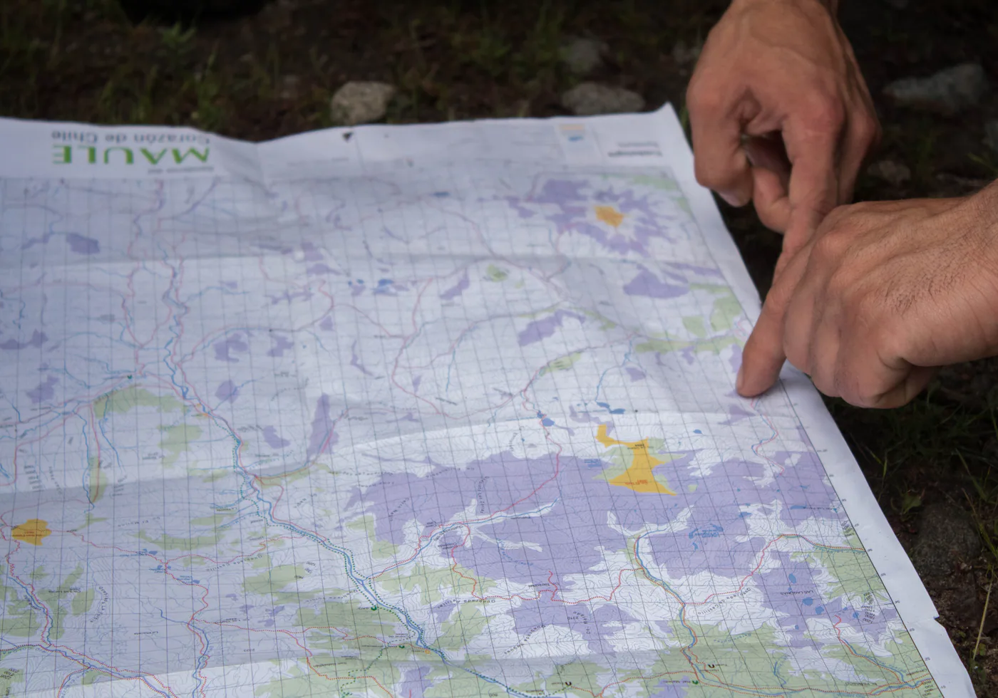 Manos revisando una carta topográfica del Maule