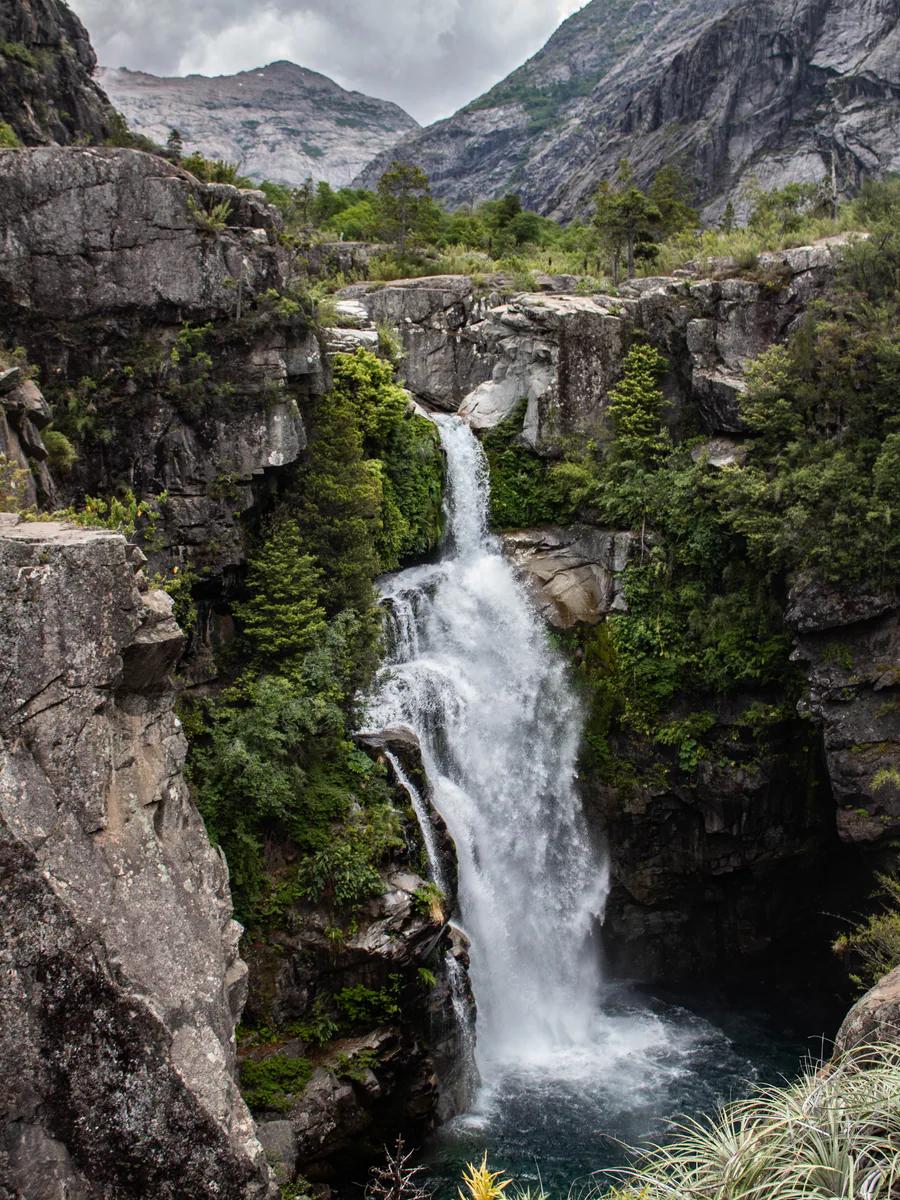 Salto de agua entre paredes rocosas y bosque del Achibueno